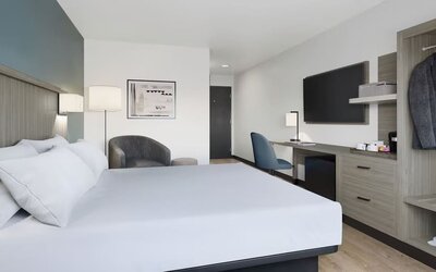 Contemporary guest room with a king bed, workspace, flat-screen TV, coffee station and open wardrobe at Hyatt Select Philadelphia Airport.