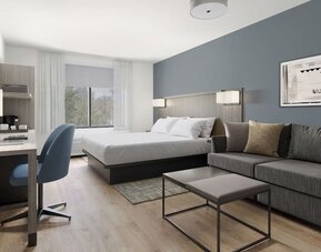 Studio-style guest room featuring a king bed, sofa, coffee table and dedicated workspace at Hyatt Select Philadelphia Airport.