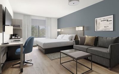 Studio-style guest room featuring a king bed, sofa, coffee table and dedicated workspace at Hyatt Select Philadelphia Airport.