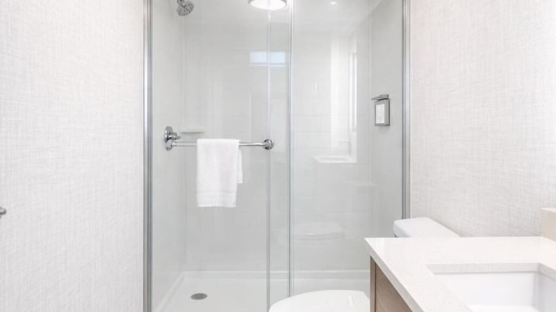 Contemporary guest bathroom with a walk-in glass shower, modern vanity, illuminated mirror and fresh towels at Hyatt Select Philadelphia Airport.