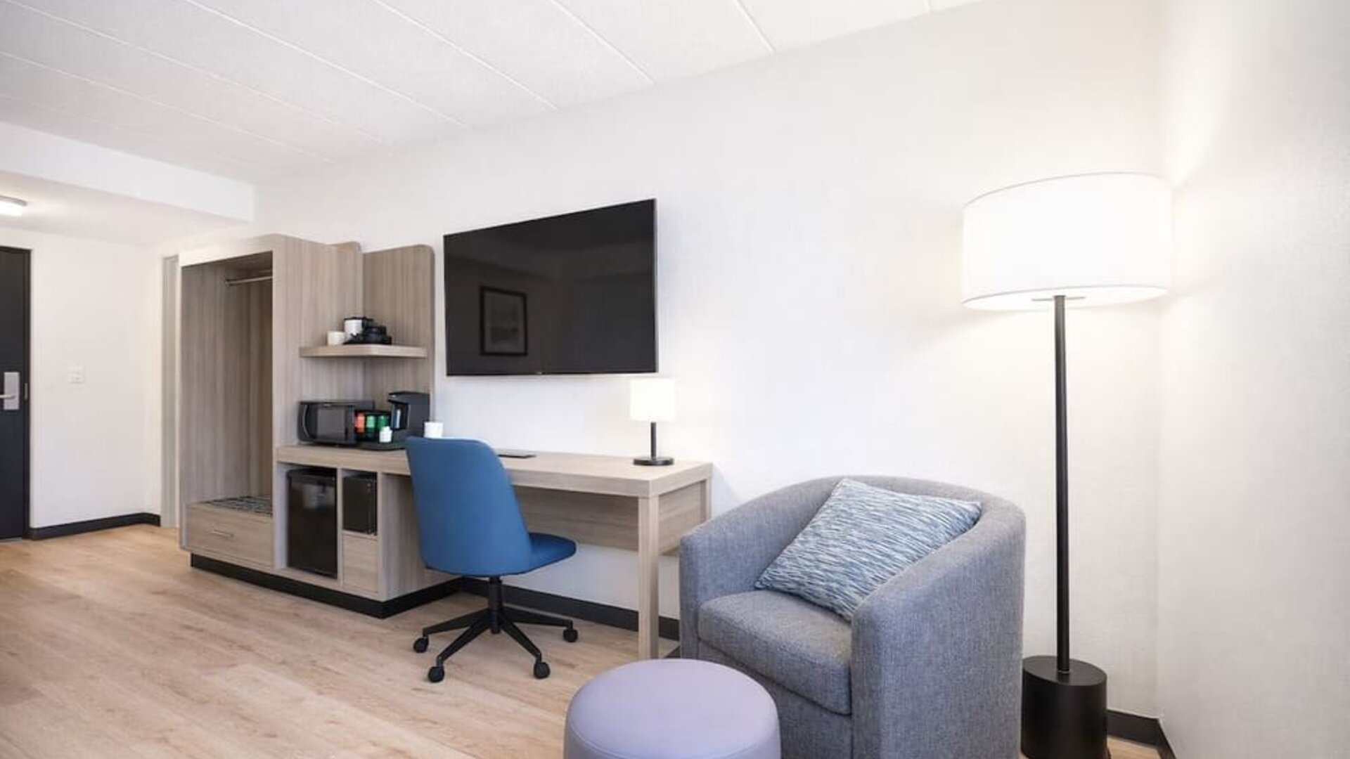 Modern guest room workspace featuring a spacious desk, ergonomic chair, flat-screen TV, mini fridge and coffee station at Hyatt Select Philadelphia Airport.