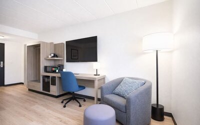 Modern guest room workspace featuring a spacious desk, ergonomic chair, flat-screen TV, mini fridge and coffee station at Hyatt Select Philadelphia Airport.