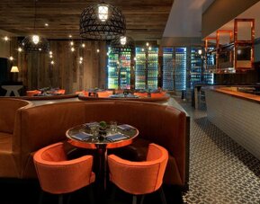 Stylish hotel restaurant with warm wood accents, cozy booth seating and illuminated wine displays at Royal Sonesta Minneapolis.
