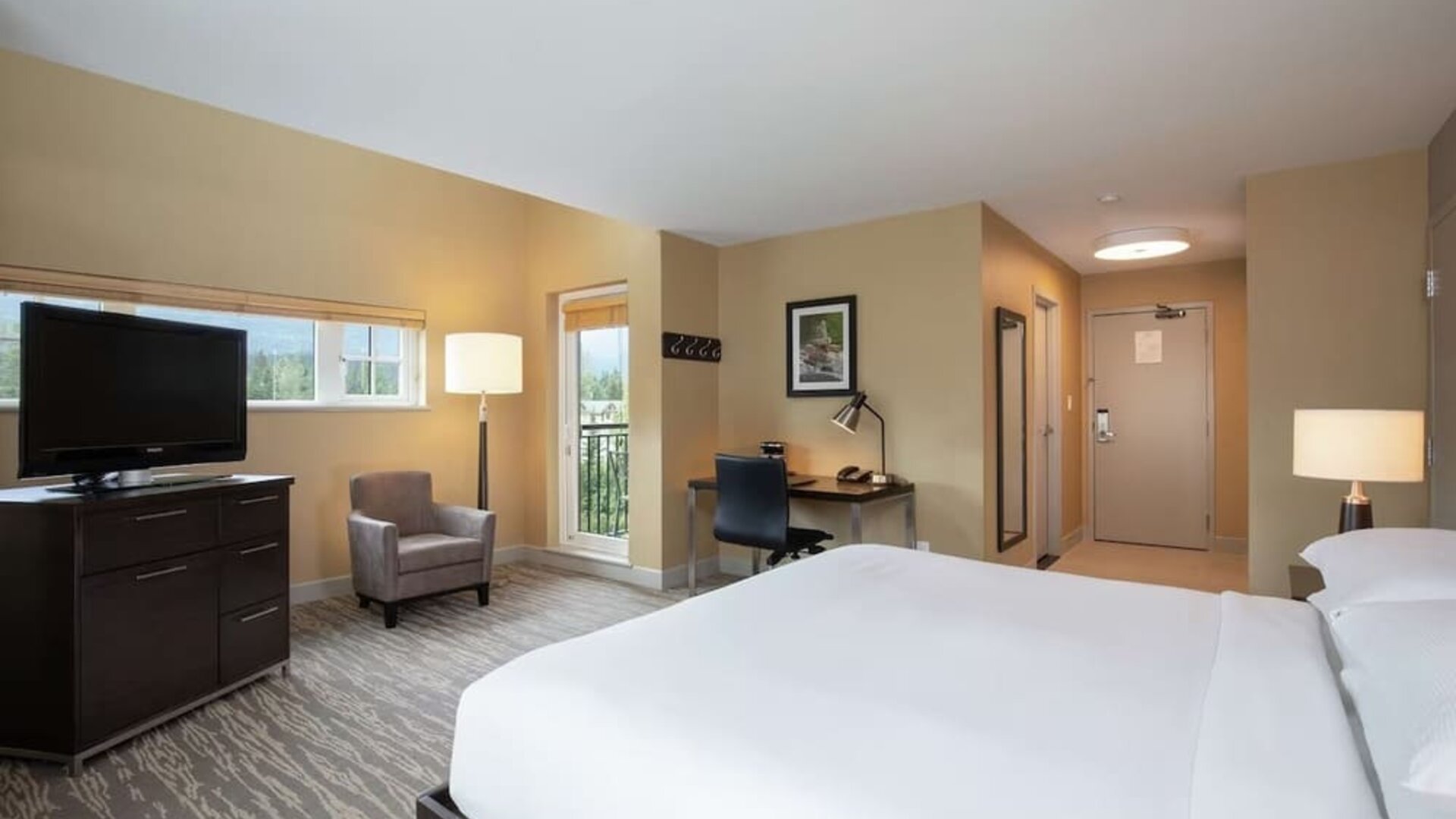 King bed with TV, terrace, workdesk and private bathroom at Hilton Whistler Resort & Spa.