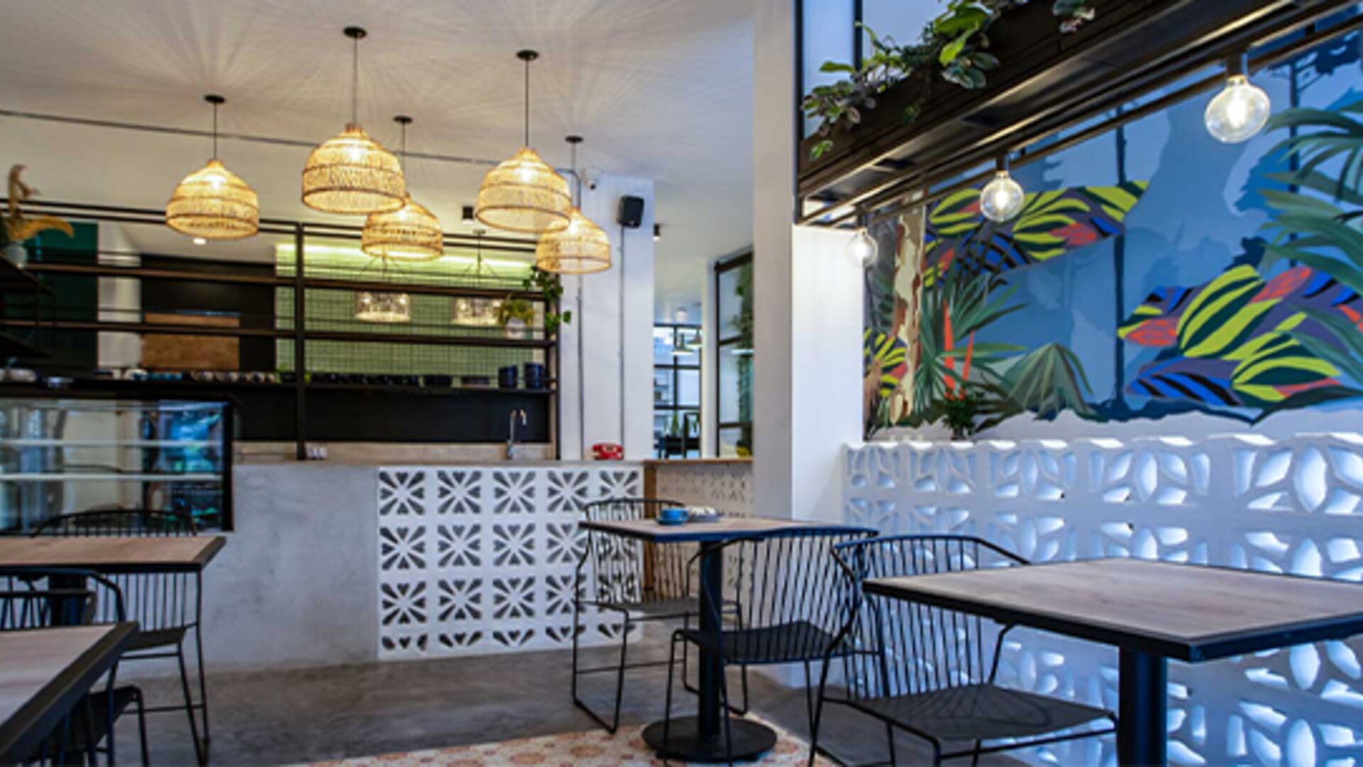 Stylish dining area at 103 Wonderful House featuring colorful tropical wall art, pendant lighting and café-style seating.