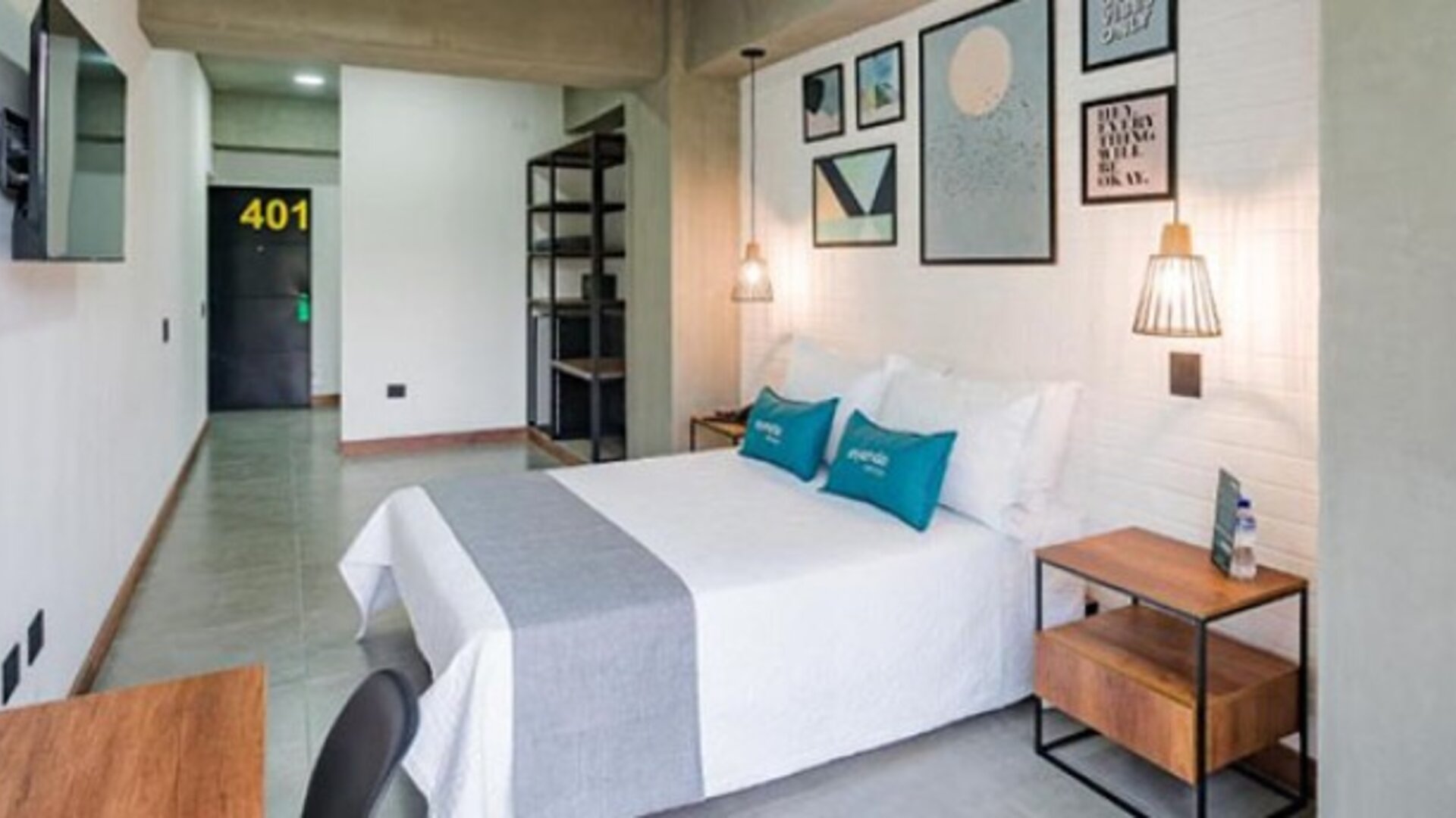 Spacious guest room at Hotel Loft 32 featuring a comfortable bed, bedside tables, wall-mounted TV and modern artwork.
