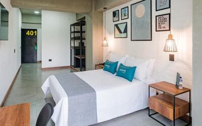 Spacious guest room at Hotel Loft 32 featuring a comfortable bed, bedside tables, wall-mounted TV and modern artwork.