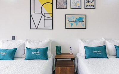 Guest room at Hotel Loft 32 featuring two beds with teal accent cushions and contemporary framed artwork.