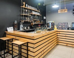 Café counter at Hotel Loft 32 featuring wooden finishes, bar stools and beverage service equipment.