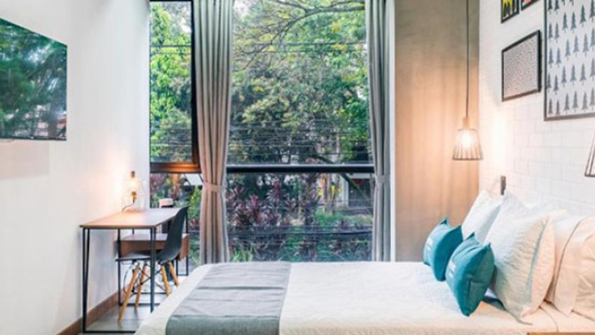Guest room at Hotel Loft 32 featuring a comfortable bed, large windows, workspace and modern pendant lighting.