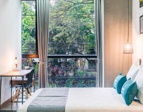 Guest room at Hotel Loft 32 featuring a comfortable bed, large windows, workspace and modern pendant lighting.