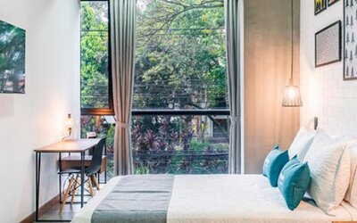Guest room at Hotel Loft 32 featuring a comfortable bed, large windows, workspace and modern pendant lighting.