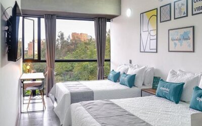 Guest room at Hotel Loft 32 featuring two beds, large windows, a workspace and colorful contemporary wall art.