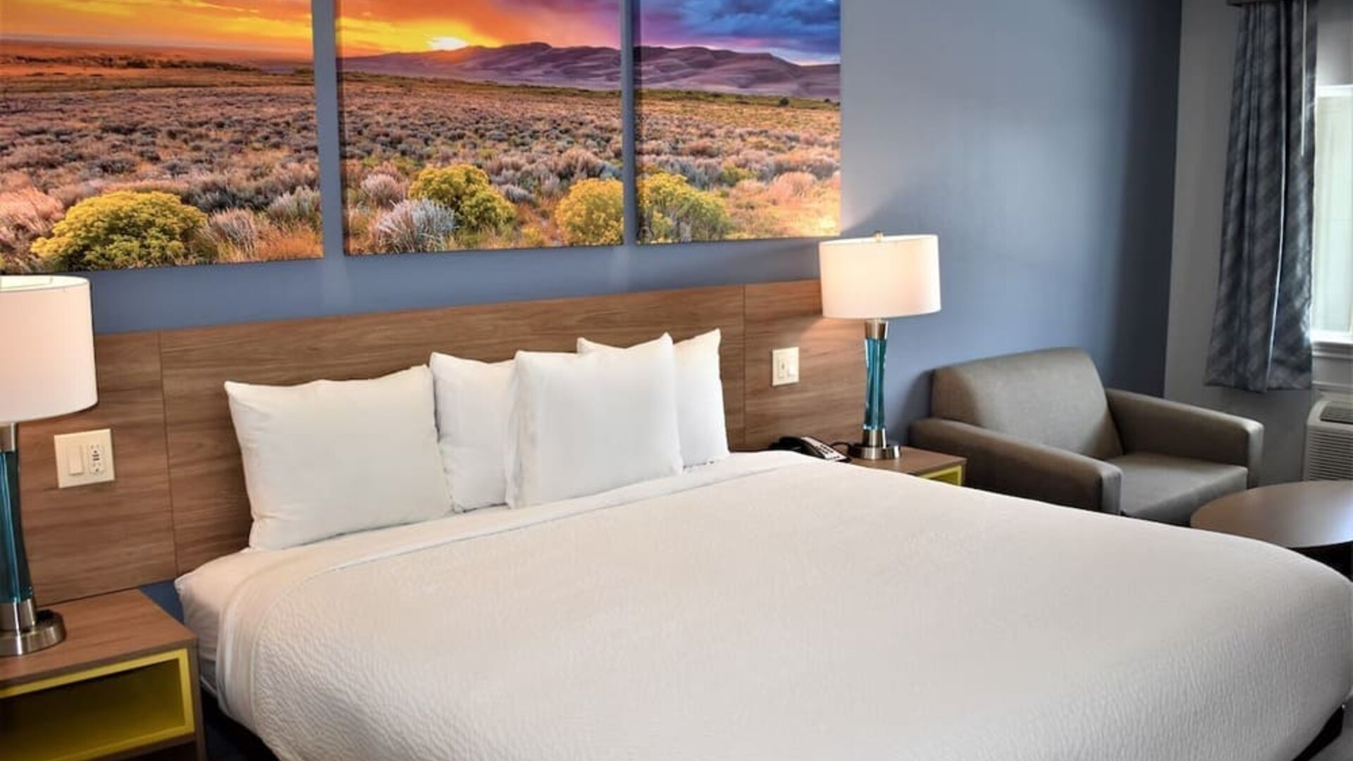 King guest room at Days Inn & Suites By Wyndham Downtown/University Of Houston featuring a king bed, bedside lamps and a seating area.