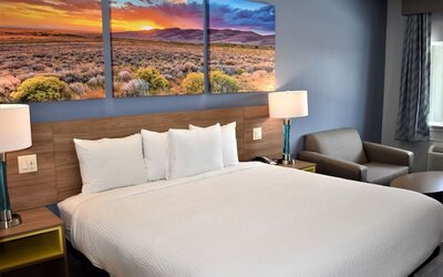 King guest room at Days Inn & Suites By Wyndham Downtown/University Of Houston featuring a king bed, bedside lamps and a seating area.