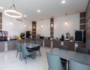 Breakfast and dining area at Days Inn & Suites By Wyndham Downtown/University Of Houston featuring dining tables, beverage stations and breakfast facilities.