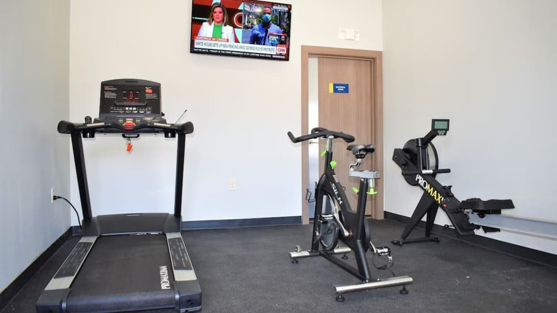 Fitness center at Days Inn & Suites By Wyndham Downtown/University Of Houston featuring a treadmill, exercise bike, rowing machine and wall-mounted TV.