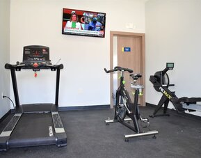 Fitness center at Days Inn & Suites By Wyndham Downtown/University Of Houston featuring a treadmill, exercise bike, rowing machine and wall-mounted TV.