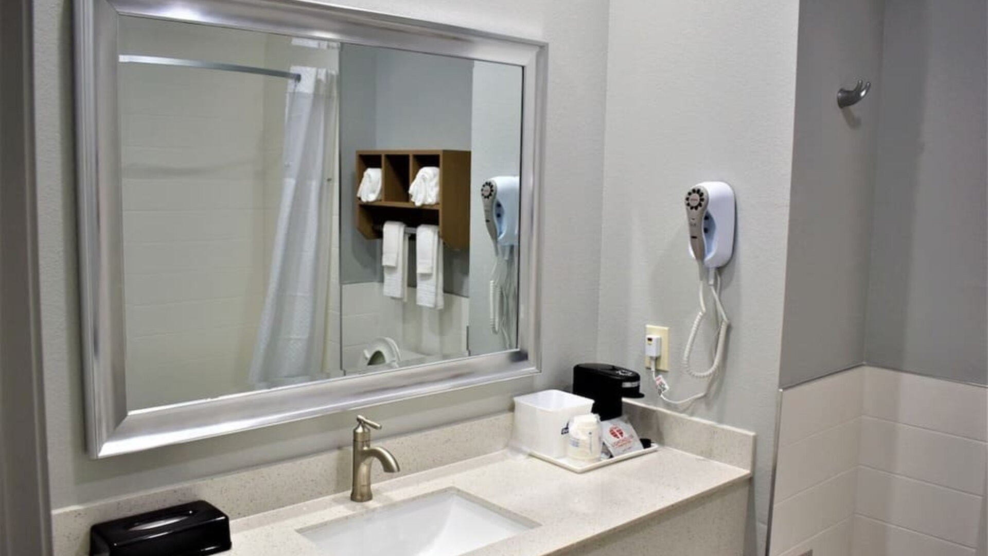 Bathroom vanity at Days Inn & Suites By Wyndham Downtown/University Of Houston featuring a large mirror, sink, hair dryer and countertop amenities.
