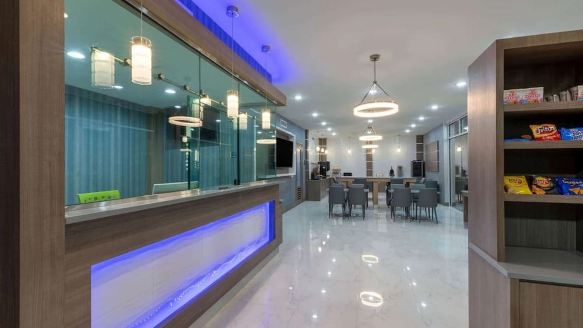 Hotel lobby at Days Inn & Suites By Wyndham Downtown/University Of Houston featuring a modern reception area, dining tables and snack display.