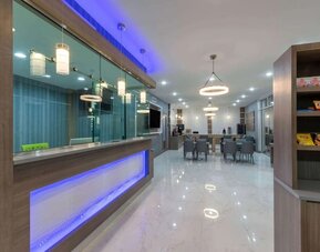 Hotel lobby at Days Inn & Suites By Wyndham Downtown/University Of Houston featuring a modern reception area, dining tables and snack display.