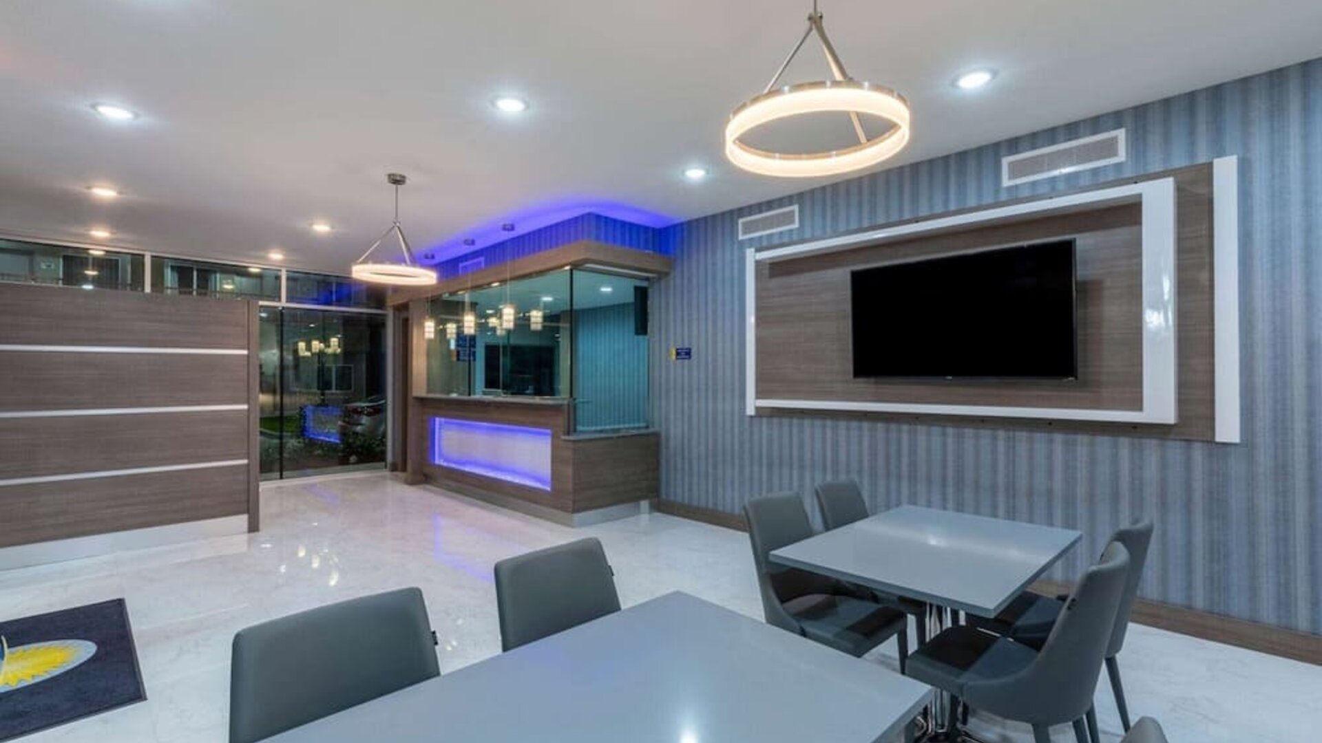 Lobby area at Days Inn & Suites By Wyndham Downtown/University Of Houston featuring dining tables, modern lighting and a wall-mounted TV.