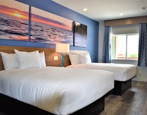 Guest room at Days Inn & Suites By Wyndham Downtown/University Of Houston featuring two beds, a large window and natural light.