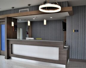 Reception desk at Days Inn & Suites By Wyndham Downtown/University Of Houston featuring contemporary wood finishes and pendant lighting.