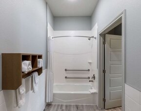 Guest bathroom at Days Inn & Suites By Wyndham Downtown/University Of Houston featuring a shower-tub combination, grab bars and towel storage.