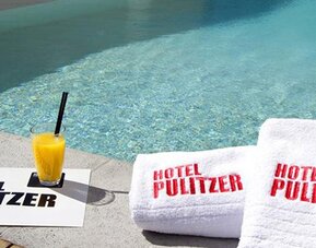 Swimming pool at Hotel Pulitzer Buenos Aires featuring poolside towels and a refreshing drink.