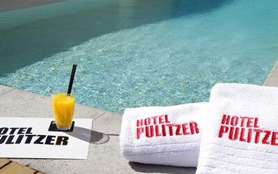 Swimming pool at Hotel Pulitzer Buenos Aires featuring poolside towels and a refreshing drink.