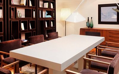 Meeting room at Hotel Pulitzer Buenos Aires featuring a large central table, upholstered chairs, bookshelves and contemporary lighting.
