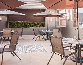 Outdoor dining terrace at NH Collection Mexico City Centro Histórico featuring tables, chairs and large patio umbrellas.