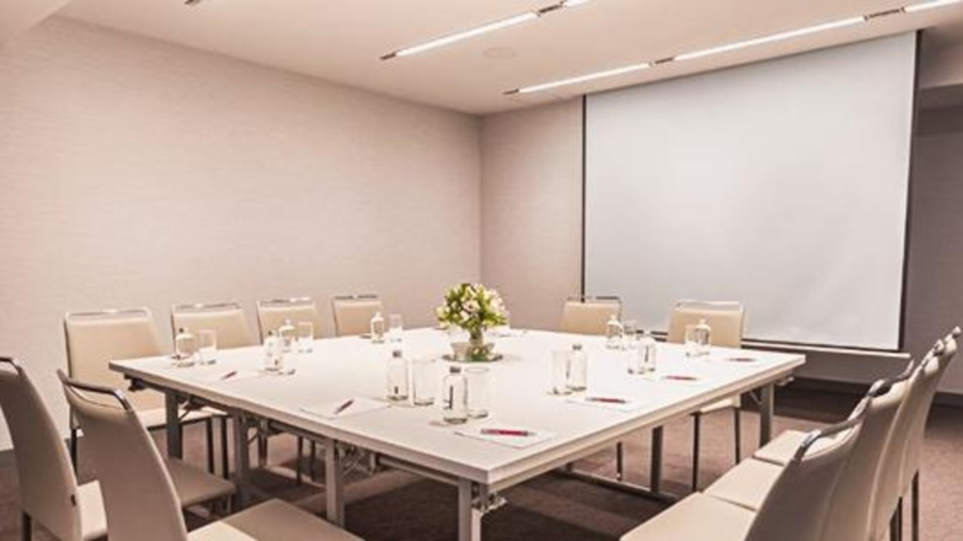 Meeting room at NH Collection Mexico City Centro Histórico featuring a conference table, chairs and projection screen.