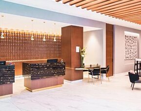 Reception area at NH Collection Mexico City Centro Histórico featuring modern front desks, lounge seating and warm wood accents.