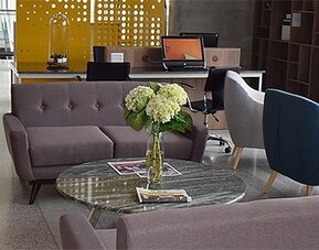 Lobby seating area at Holiday Inn Lima Airport featuring modern sofas, blue armchairs, a glass coffee table and fresh flowers.