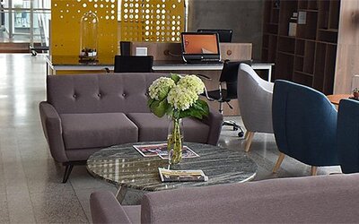 Lobby seating area at Holiday Inn Lima Airport featuring modern sofas, blue armchairs, a glass coffee table and fresh flowers.