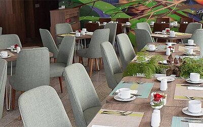 Restaurant at Holiday Inn Lima Airport featuring neatly arranged dining tables, upholstered chairs and colorful wall artwork.