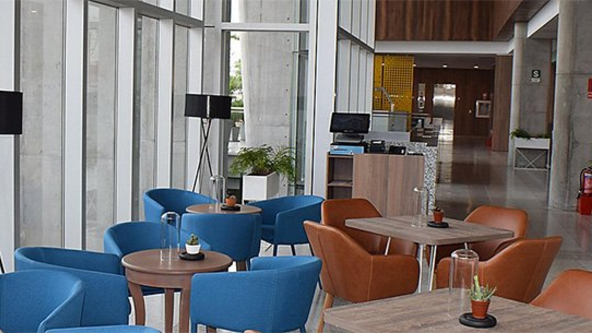 Dining area at Holiday Inn Lima Airport featuring colorful seating, café-style tables and floor-to-ceiling windows.