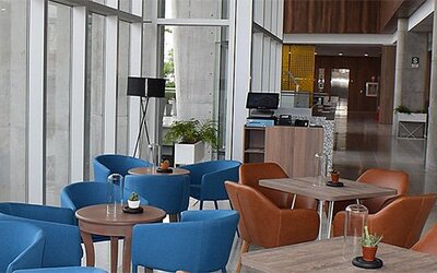 Dining area at Holiday Inn Lima Airport featuring colorful seating, café-style tables and floor-to-ceiling windows.
