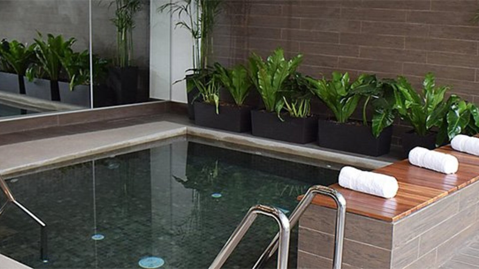 Pool at Holiday Inn Lima Airport featuring tiled surroundings, poolside towels and decorative greenery.