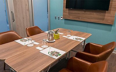 Meeting room at Holiday Inn Lima Airport featuring a conference table, leather chairs, presentation materials and a wall-mounted screen.
