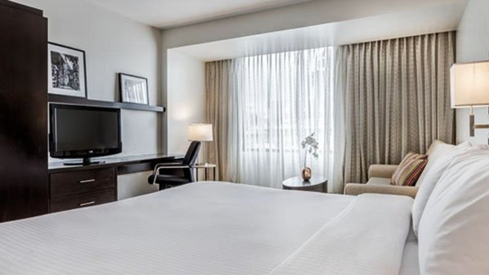 Bright guest room at Courtyard Panama Metromall featuring a king bed, television, work area, armchair and large window.