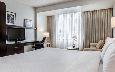 Bright guest room at Courtyard Panama Metromall featuring a king bed, television, work area, armchair and large window.