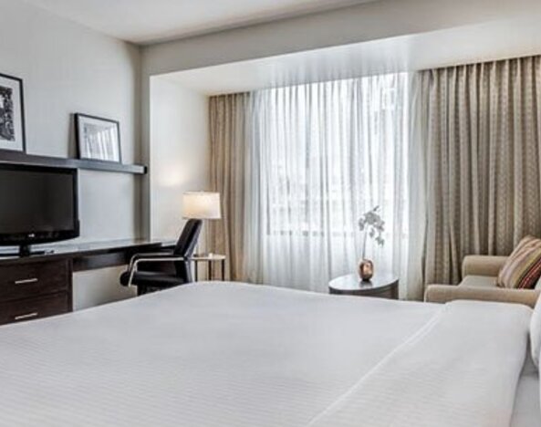 Bright guest room at Courtyard Panama Metromall featuring a king bed, television, work area, armchair and large window.