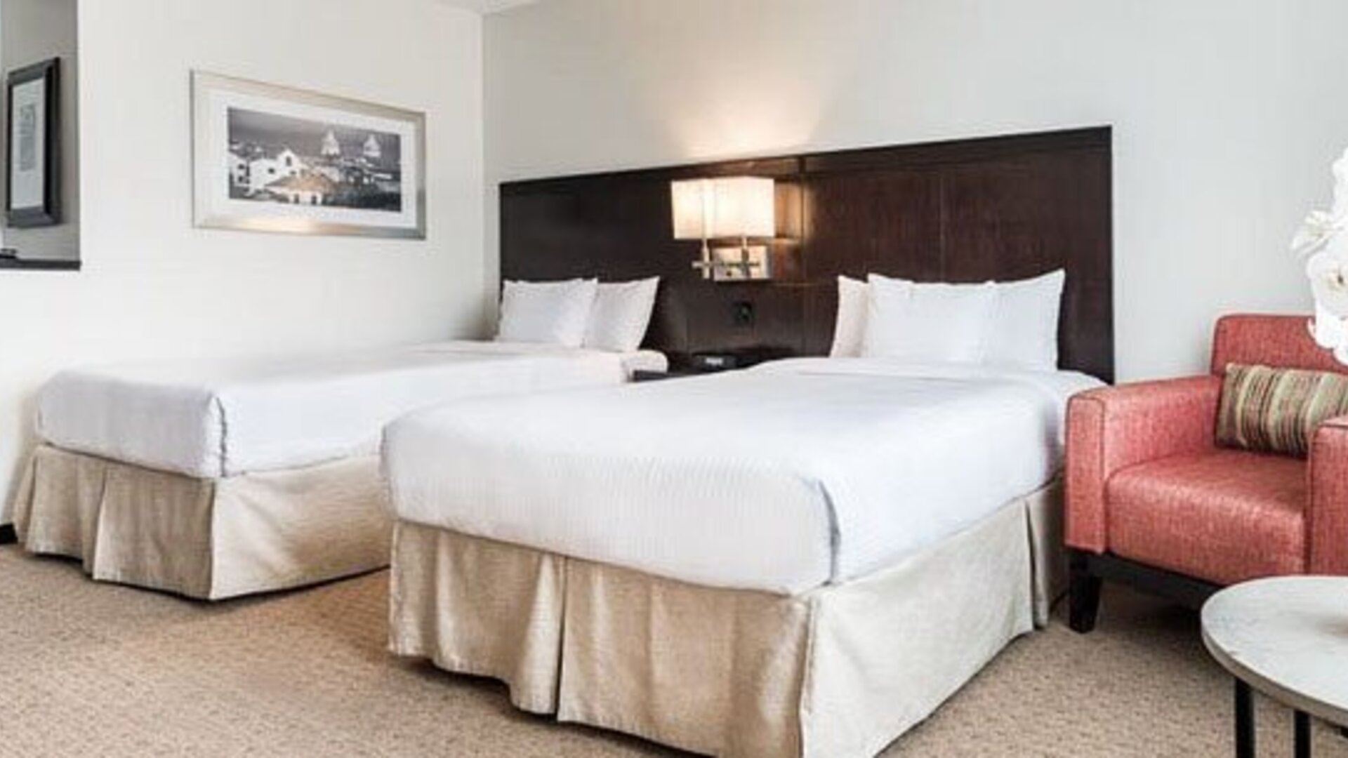 Double guest room at Courtyard Panama Metromall featuring two beds, an armchair, side table and contemporary dark wood headboard.