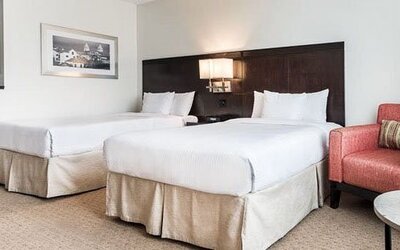 Double guest room at Courtyard Panama Metromall featuring two beds, an armchair, side table and contemporary dark wood headboard.