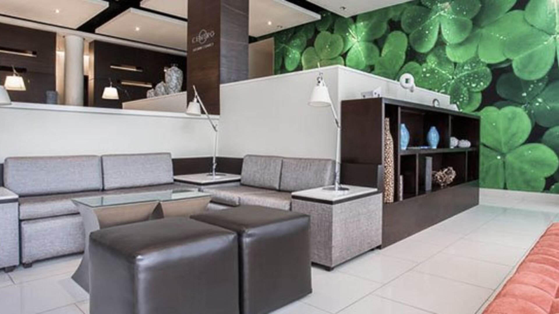 Lobby seating area at Courtyard Panama Metromall featuring sofas, ottomans, individual reading lamps and a green feature wall.