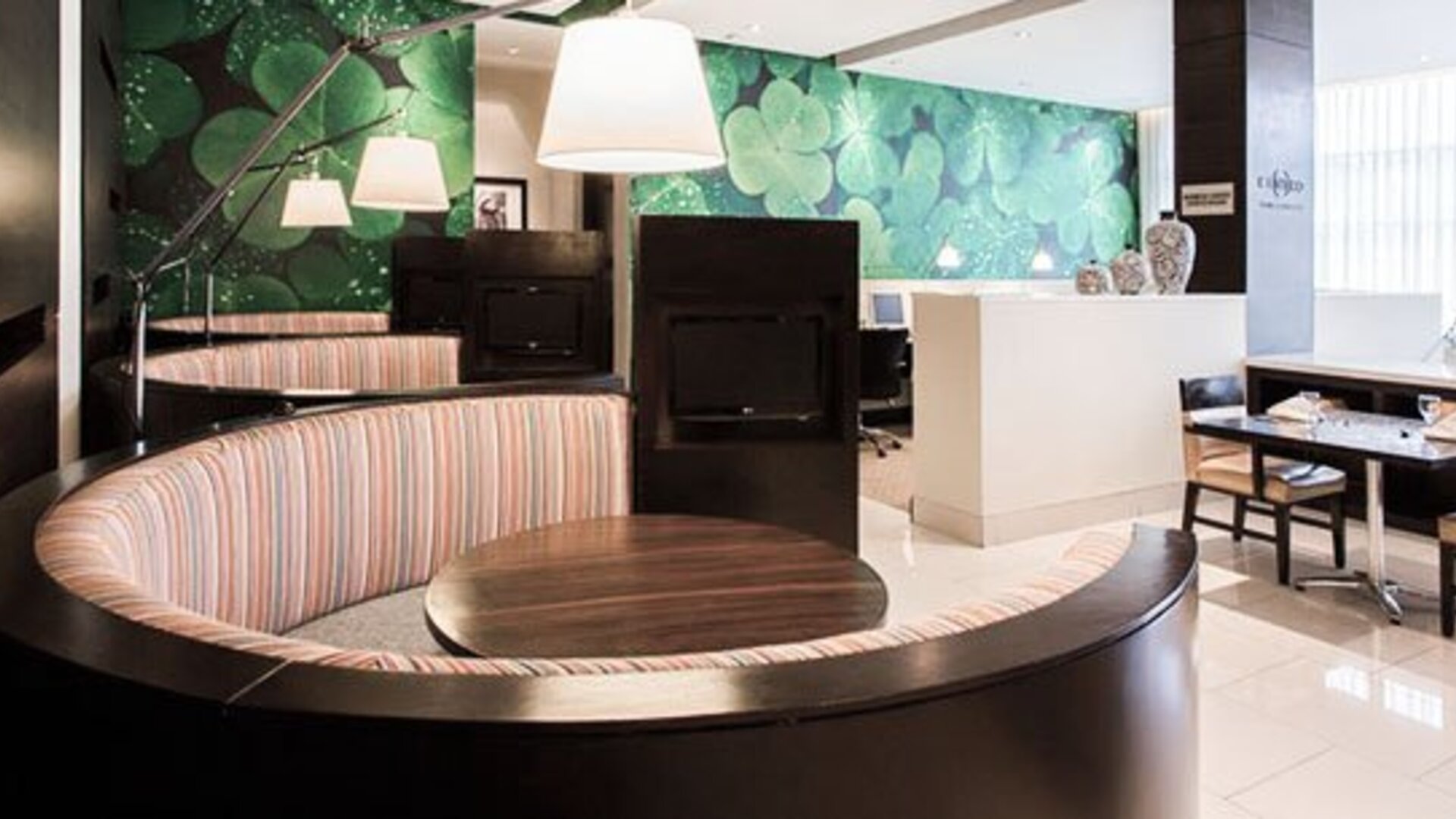 Lobby workspace at Courtyard Panama Metromall featuring curved booth seating, tables and contemporary pendant lighting.