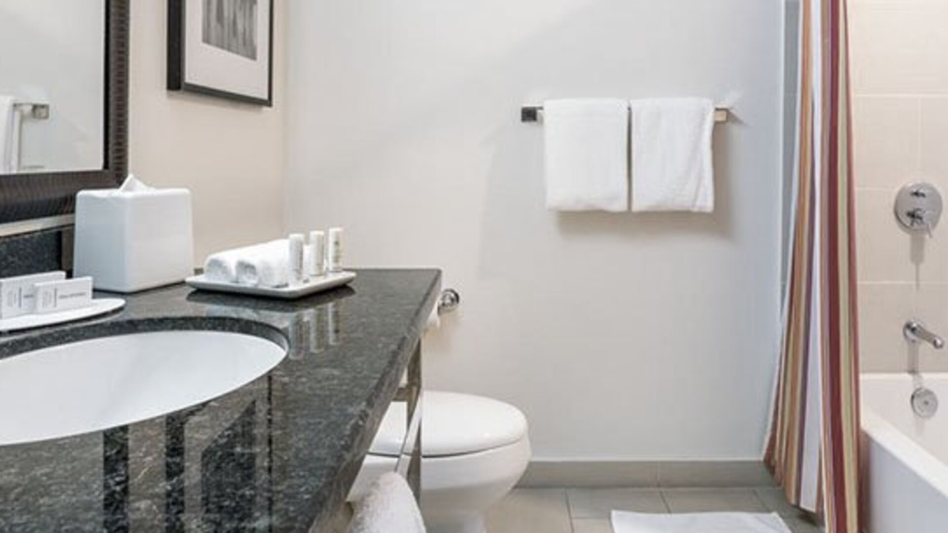 Guest bathroom at Courtyard Panama Metromall featuring a granite vanity, bathtub with shower and complimentary toiletries.